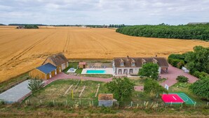 A rural property with a large field, a swimming pool, and a tennis court.