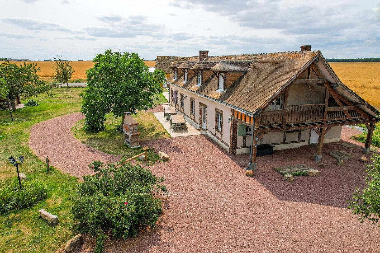 A traditional building with a gravel driveway, a wooden porch, and a stone fireplace.