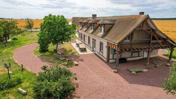 A traditional building with a gravel driveway, a wooden porch, and a stone fireplace.