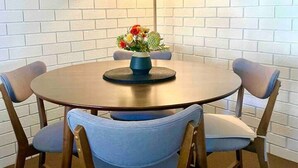 Une table ronde avec quatre chaises, un vase rempli de fleurs, un lampadaire et un miroir accroché au mur.