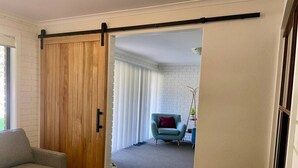 Une pièce avec une porte coulissante de style grange, un canapé gris, un fauteuil bleu et un mur en briques blanches.