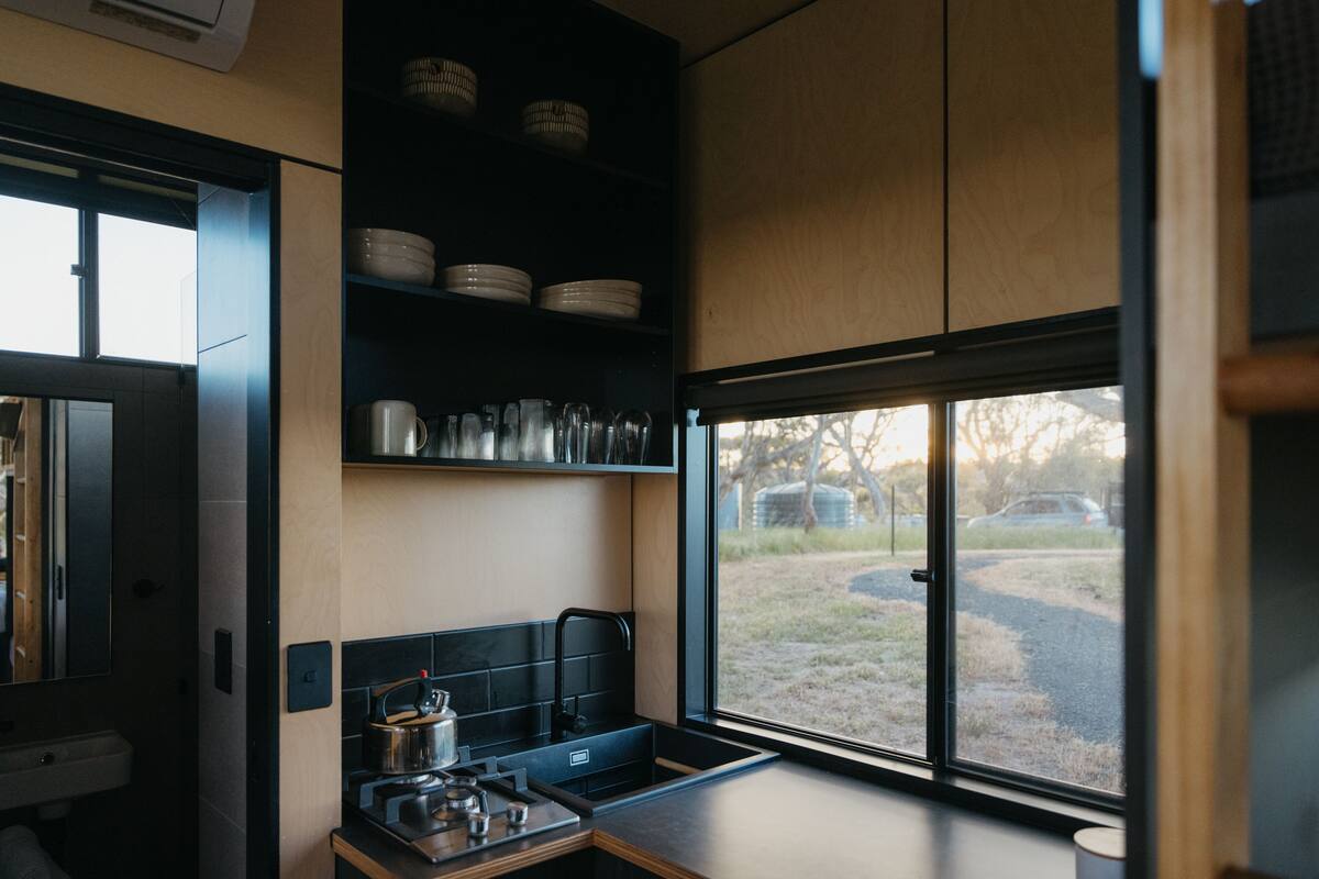 A modern kitchen with a built-in stove, sink, and black shelving unit.