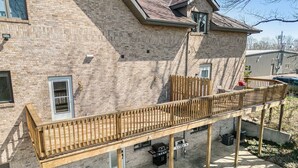 Un bâtiment en briques doté d’une terrasse en bois et d’un espace barbecue extérieur.