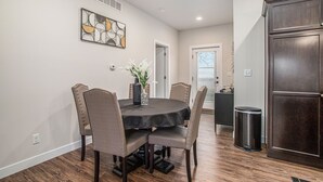 Un coin repas comprenant une table ronde, quatre chaises, un vase avec des fleurs et un élément décoratif mural.
