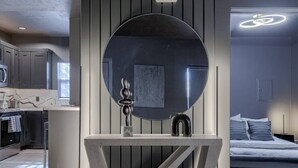 Una cocina moderna con armarios oscuros, una isla central y un espejo redondo grande sobre un lavabo.