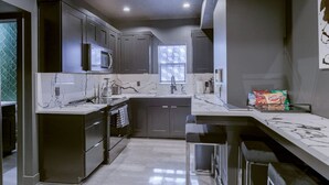 Una cocina moderna con armarios oscuros, microondas, lavamanos y ventana.