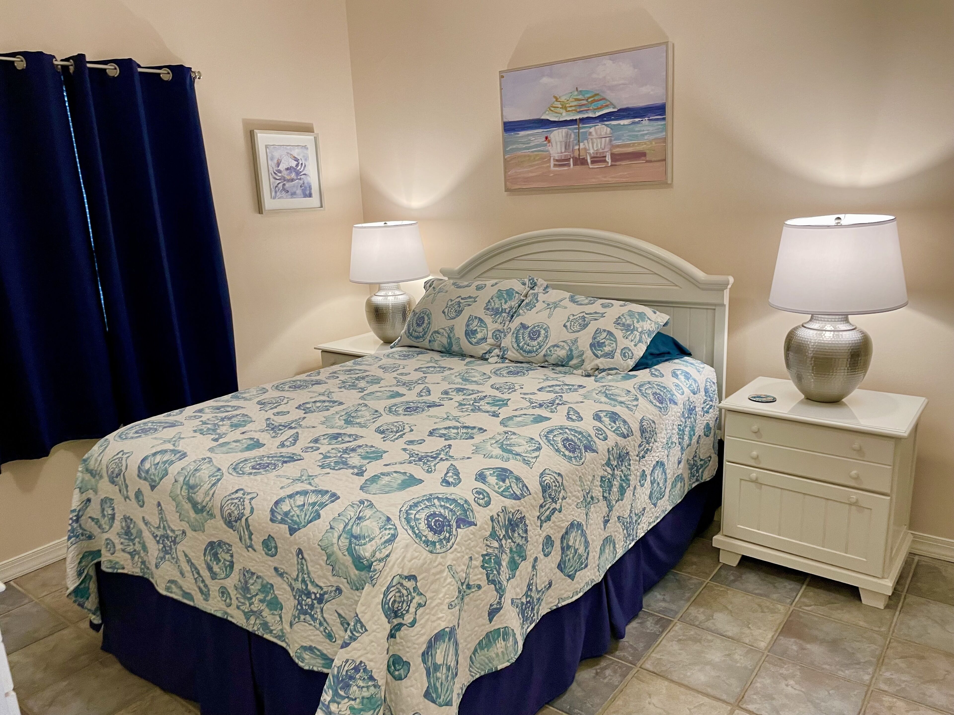 Een slaapkamer met een bed, twee nachtkastjes, een lamp, een schilderij en een gordijn.