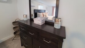 Une commode en bois sombre, surmontée d’un grand miroir, et agrémentée de deux vases décoratifs et d’une boîte sur laquelle est inscrit : « Trouvez la joie dans le voyage. »