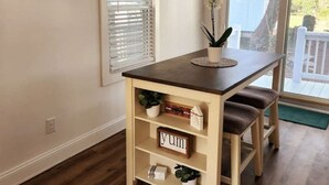 Une petite table en bois avec un plateau foncé, une plante en pot et un panneau indiquant « délicieux » placé sur une étagère.