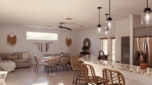 Una cocina moderna con encimera de mármol, electrodomésticos de acero inoxidable y una zona de comedor con sillas de mimbre y una mesa de vidrio.