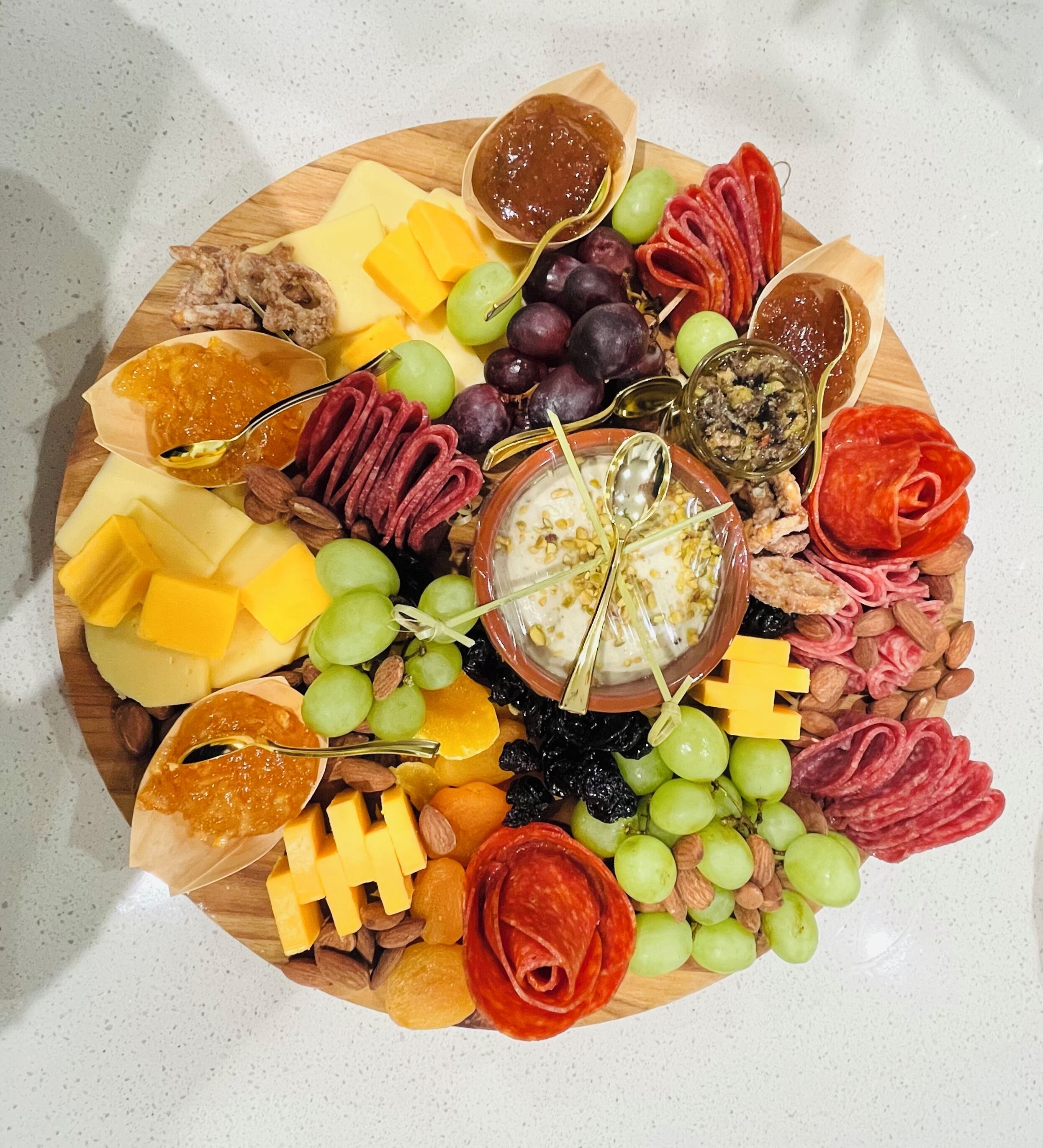A charcuterie board with various cheeses, meats, fruits, and nuts.