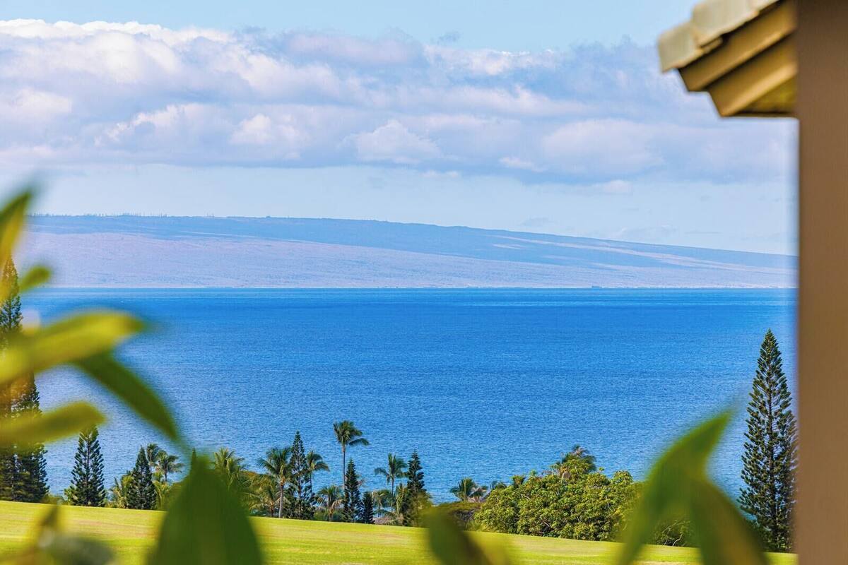 A coastal view with a clear sky, a calm sea, and a distant mountain range.