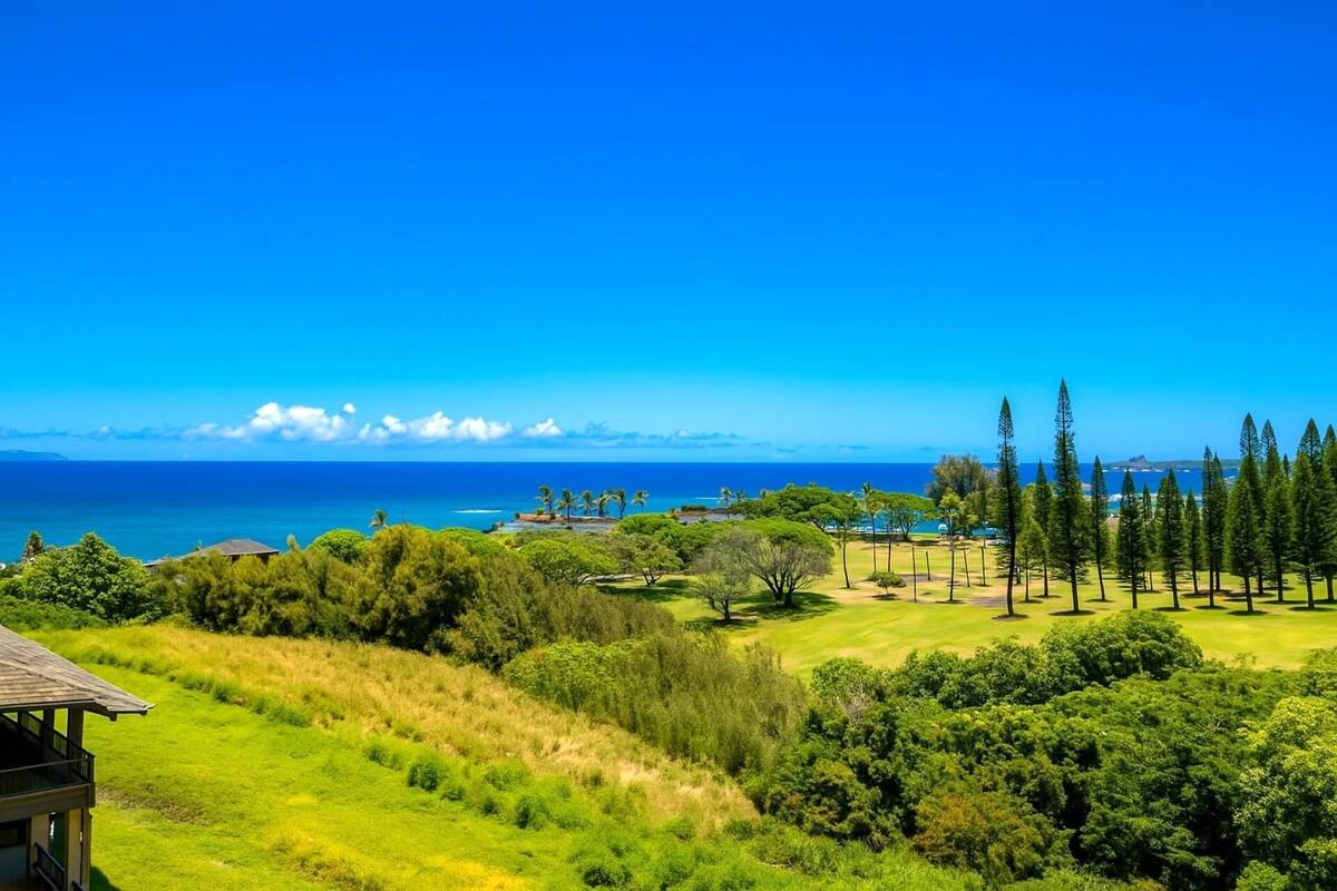 A coastal landscape with a golf course, trees, and a clear blue sky.