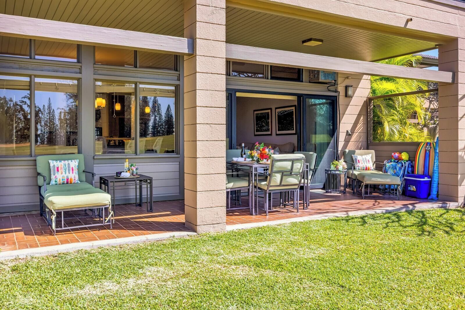 A covered patio with outdoor seating, a dining table, and a small garden area.