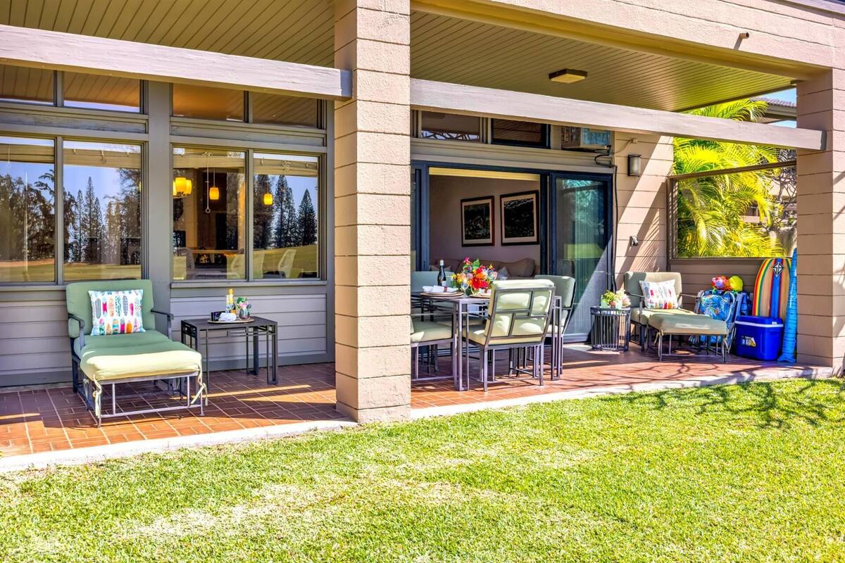 A covered patio area with outdoor seating, a dining table, and a view of the surrounding landscape.