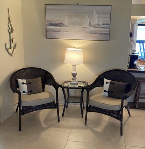 Two wicker chairs with cushions, a small table with a lamp, and a painting of sailboats on the wall. - The Villages, 2BR-2BA House Close to Spanish Springs Town Square (Lady Lake)
