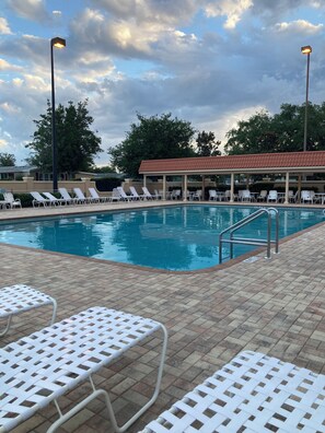 A swimming pool with white lounge chairs and a covered seating area.
