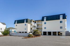 A multi-story hotel with a parking lot in front. - Oceanfront Escape | Oceanfront | Community Pool (Kill Devil Hills)