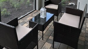 Een balkon met rieten meubilair en uitzicht op een gebouw en een bouwplaats.