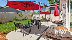 A patio with outdoor furniture, a grill, and red umbrellas.