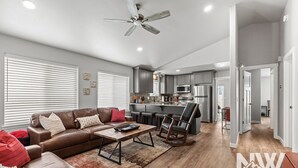 A spacious living room with a brown leather sofa, a coffee table, and a ceiling fan.
