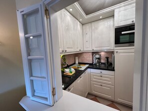 A kitchen with white cabinets, a black countertop, and a built-in microwave.
