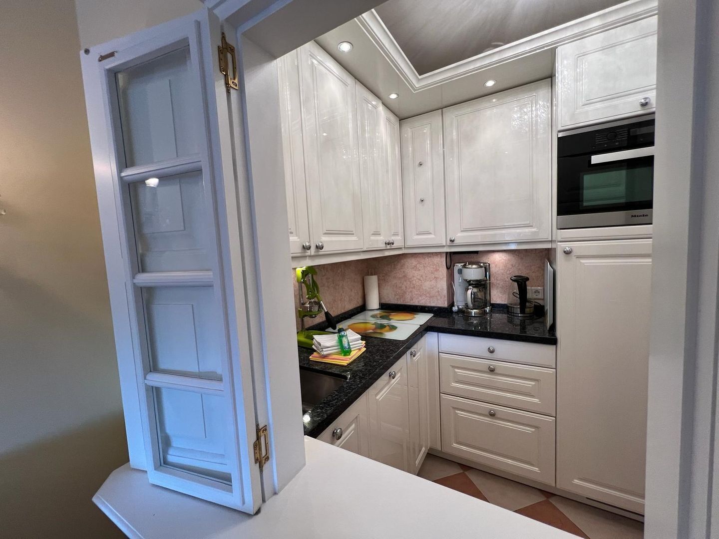 A kitchen with white cabinets, a black countertop, and a built-in microwave.