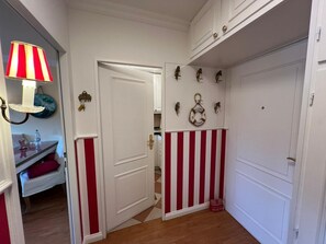 A hallway with a striped wall, a door, and a wall-mounted light fixture.