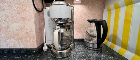 A kitchen with a coffee maker, a kettle, and a microwave.