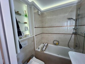 A modern bathroom with a glass shower enclosure, a bathtub, and a vanity with a mirror. - Sunapp - Individuell Ausgestattetes Appartement (Sylt)