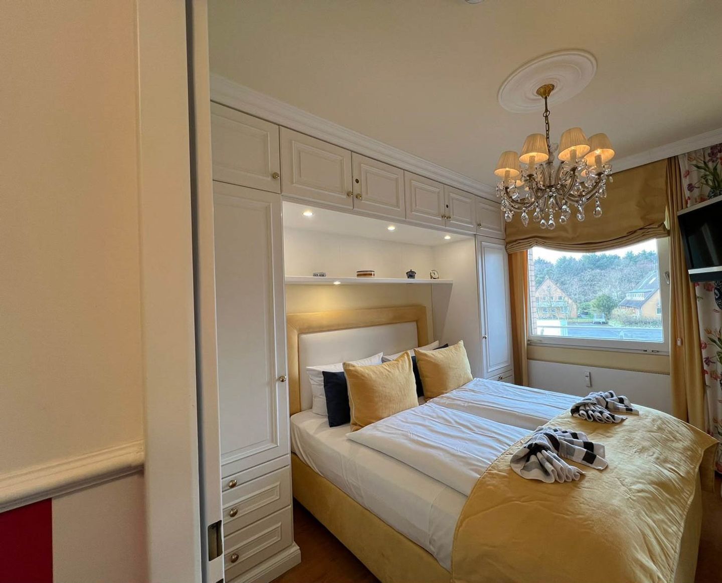 A bedroom with a bed, built-in wardrobe, and a chandelier.