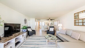 A modern living room with a TV, leather chairs, a sofa, and a dining area in the background. - Step into Paradise at South Seas Towers 4-805 (Marco Island)