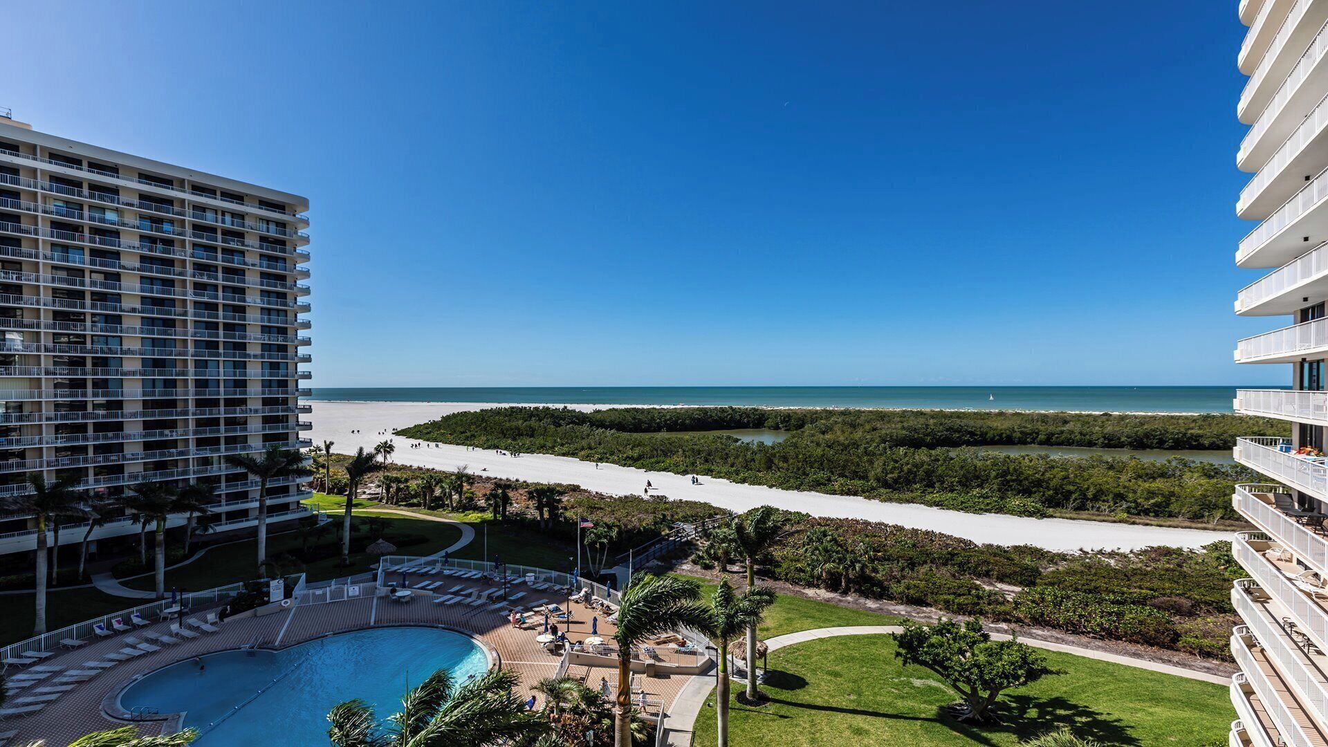 A hotel with a pool, beach view, and a mangrove area.