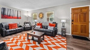 Ein Wohnzimmer mit zwei schwarzen Ledersofas, einem Couchtisch und einem gemusterten Teppich.