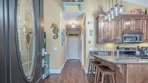 A kitchen with wooden cabinets, a large island with stools, and a microwave. - Tiki Hut W/Tiki Bar|Linens|Golf Cart|Outdoor Area (Myrtle Beach)