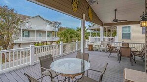 A covered outdoor deck with a glass table and chairs, surrounded by a white railing. - Tiki Hut W/Tiki Bar|Linens|Golf Cart|Outdoor Area (Myrtle Beach)