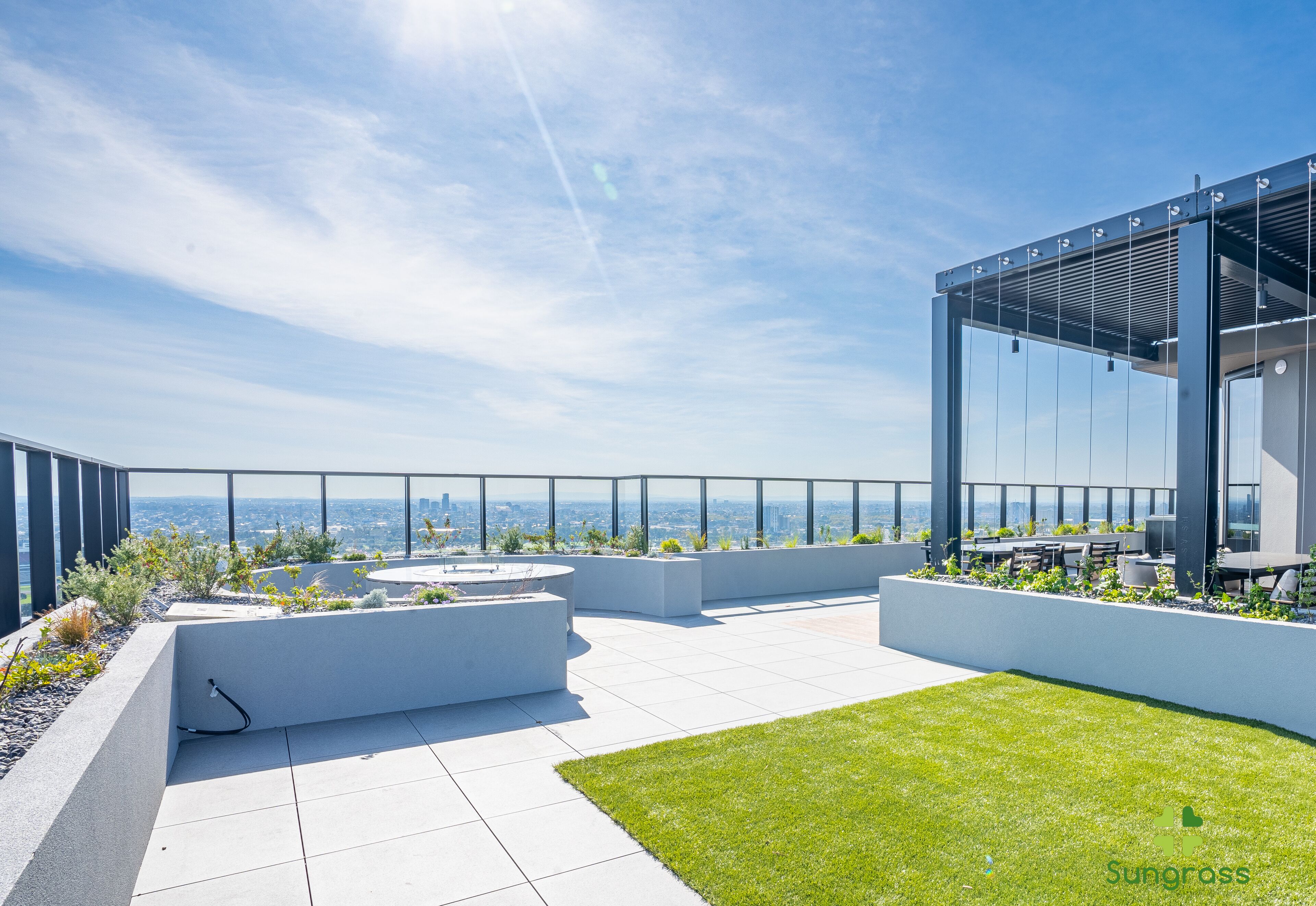 A rooftop terrace with a clear view of the city skyline, modern seating areas, and a glass-enclosed structure.
