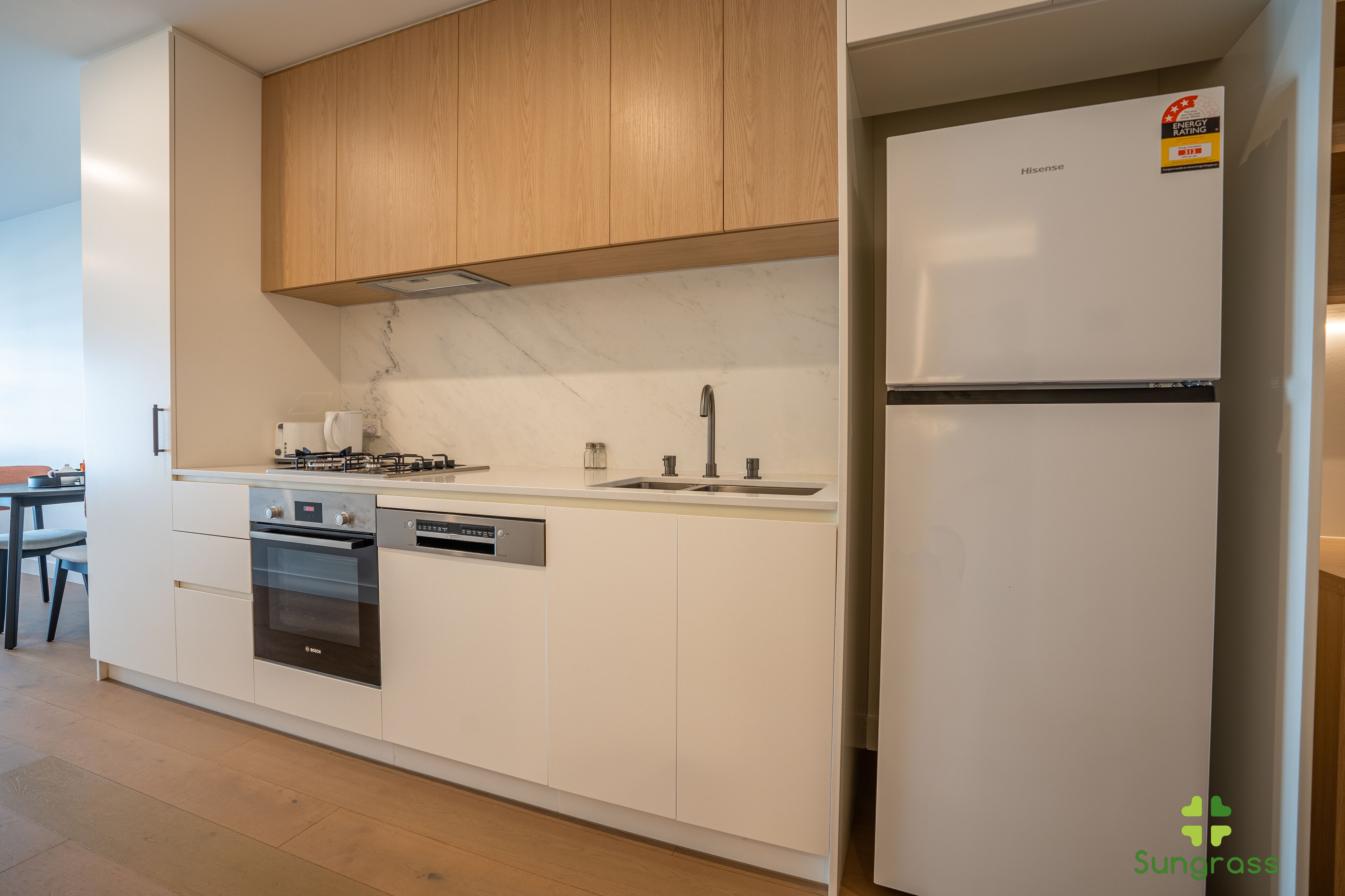 A modern kitchen with white cabinetry, a built-in oven, a dishwasher, and a refrigerator.