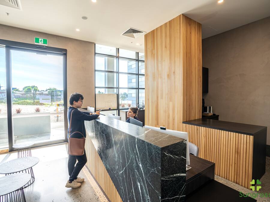 A modern reception area with a marble counter, wooden paneling, and large windows offering a view of the outdoors.