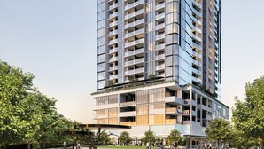 Un moderno edificio de gran altura con varios balcones, rodeado de un parque ajardinado.