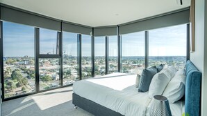 Un dormitorio moderno con una cama grande, vistas de la ciudad y un tragaluz.