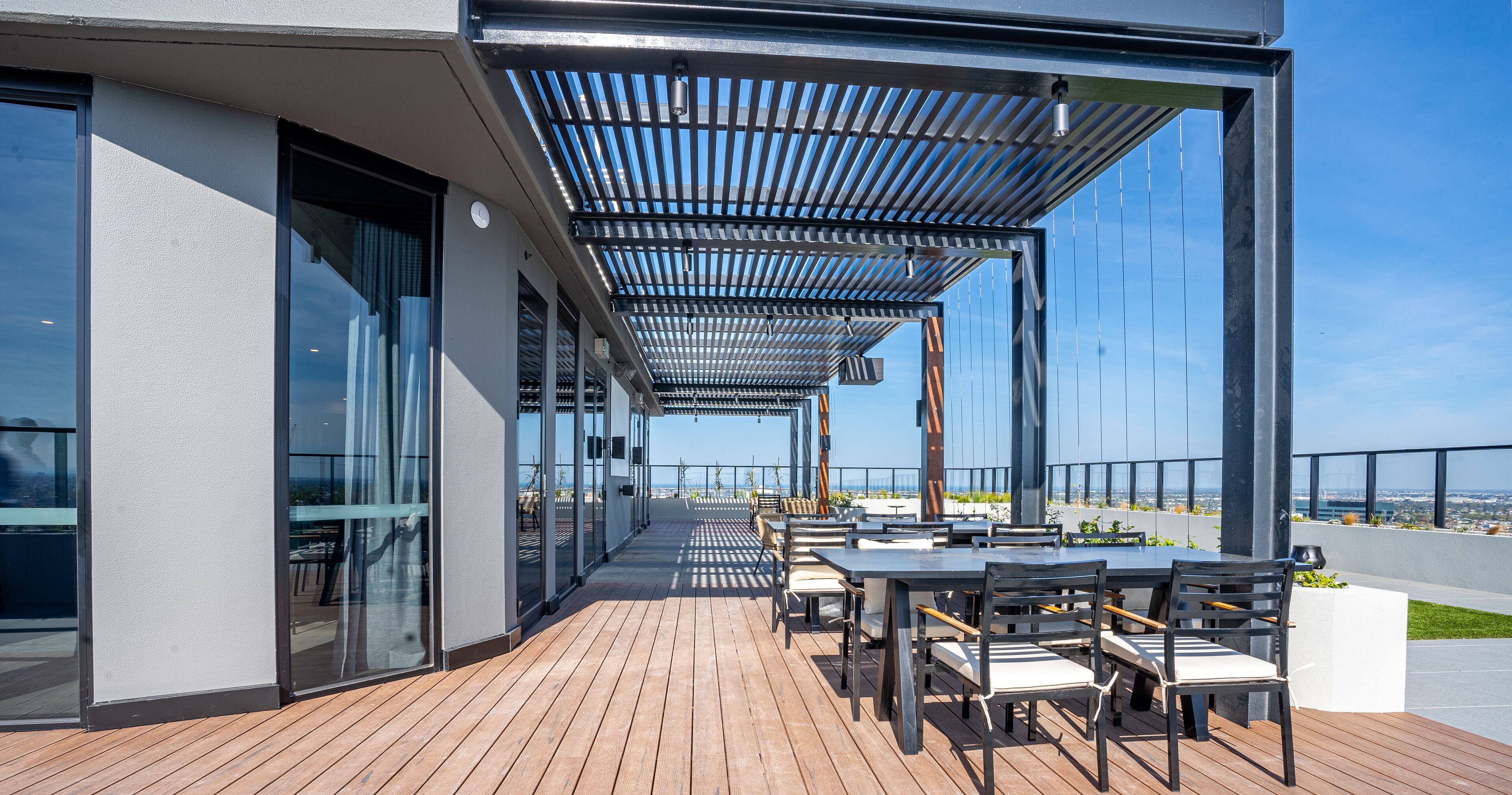 Une terrasse extérieure avec des tables et des chaises, une pergola et une vue sur la ville.
