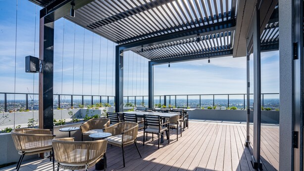 Terraza en la azotea con mobiliario exterior, una pérgola y vistas a la ciudad.