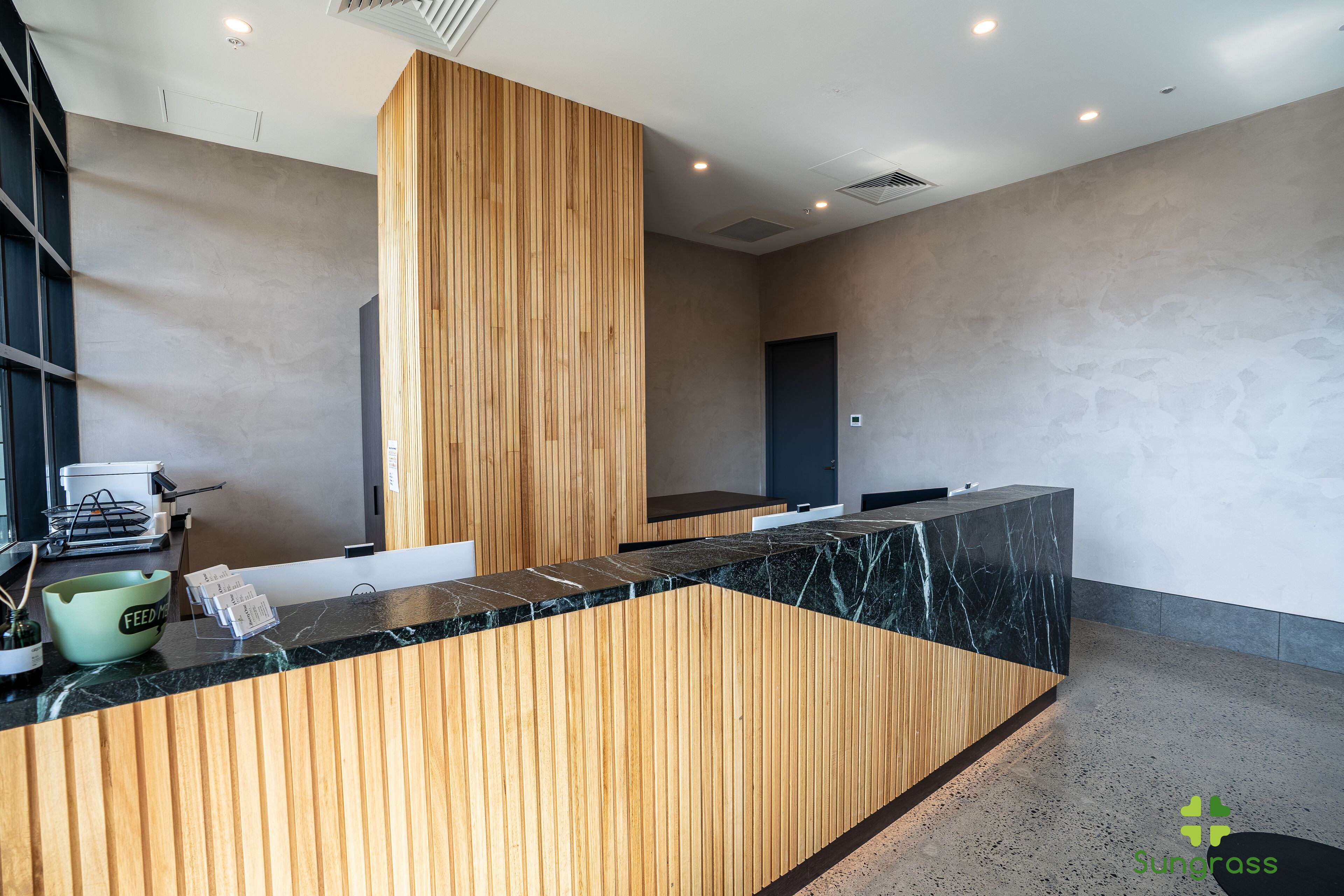 Un'area reception con scrivania in legno, bancone in marmo e design moderno.