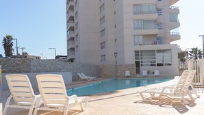 Un espace piscine avec des chaises longues et un mur en pierre.