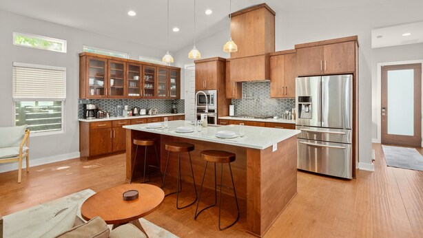 Een moderne keuken met houten kasten, roestvrijstalen apparatuur en een centraal eiland met krukken.