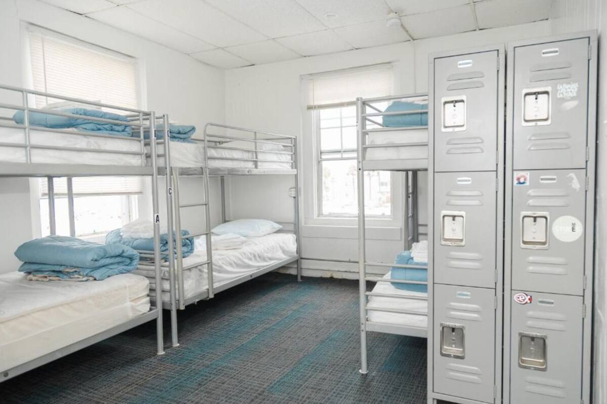 Une chambre de dortoir avec des lits superposés, une fenêtre et des casiers métalliques.