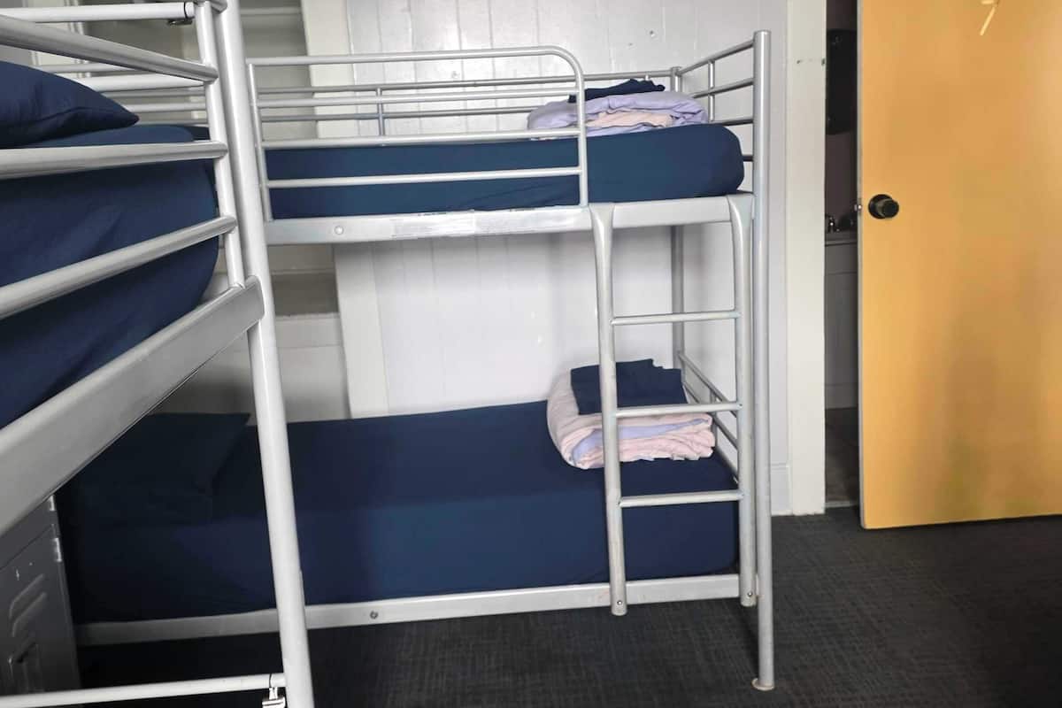 Une chambre avec un lit superposé, une porte et un sol recouvert de moquette.