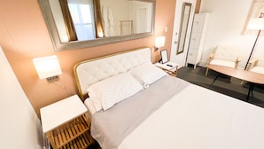 Een hotelkamer met een bed, nachtkastje, lamp, spiegel en een stoel.