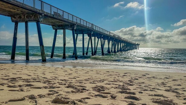 Een strand met een pier die zich uitstrekt over de oceaan.